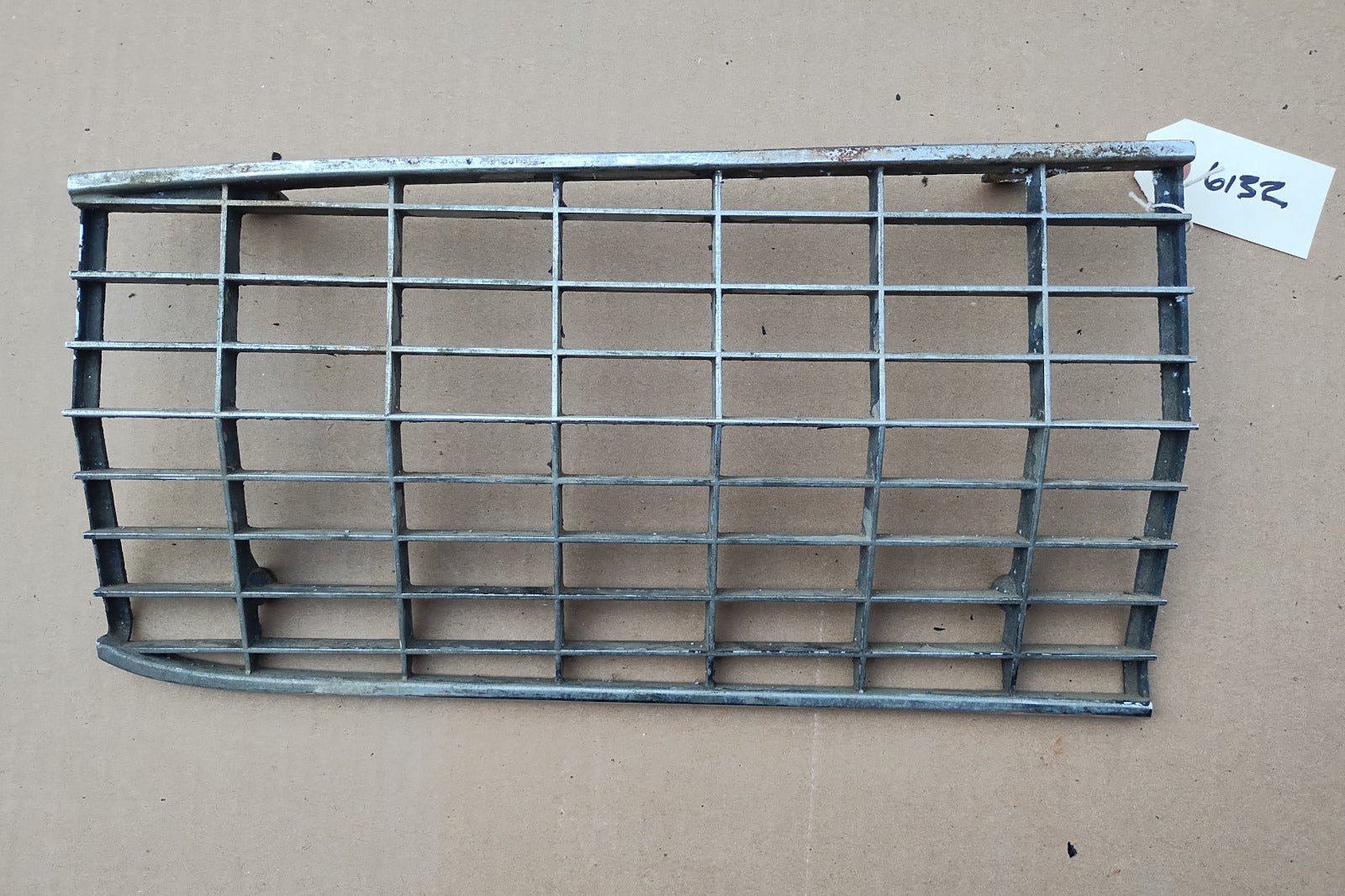 A Ford Thunderbird headlight door grille with visible signs of rust and aging, including pitting and paint peeling.